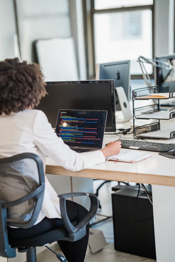 gallery-3 Focused businesswoman coding at desk in a modern office setting, showcasing concentration and technology skills.