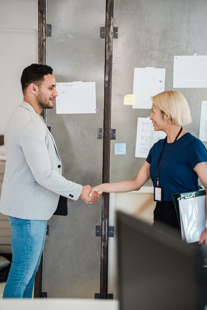 services-02 A man and woman shaking hands in a contemporary office environment, symbolizing business collaboration.