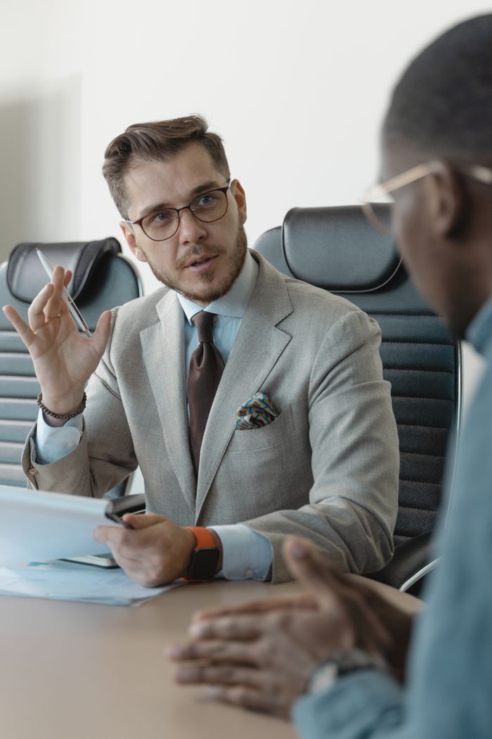 gallery-1 Two businessmen engaged in a professional meeting in a modern office setting.