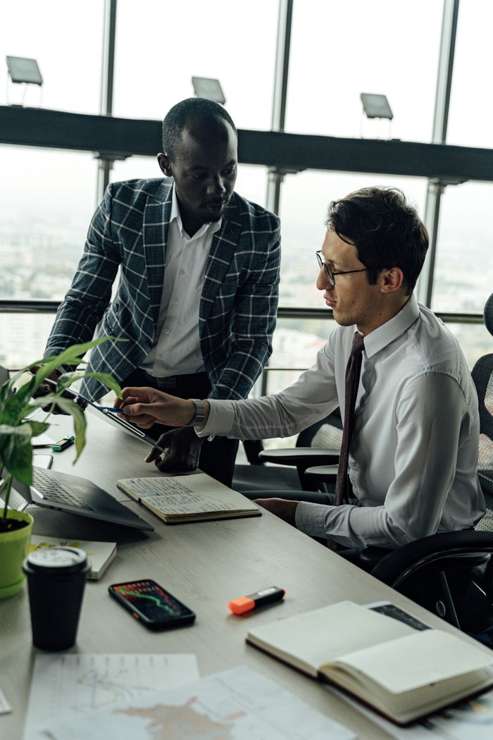 gallery-4 Two businessmen discussing projects in a modern high-rise office setting.